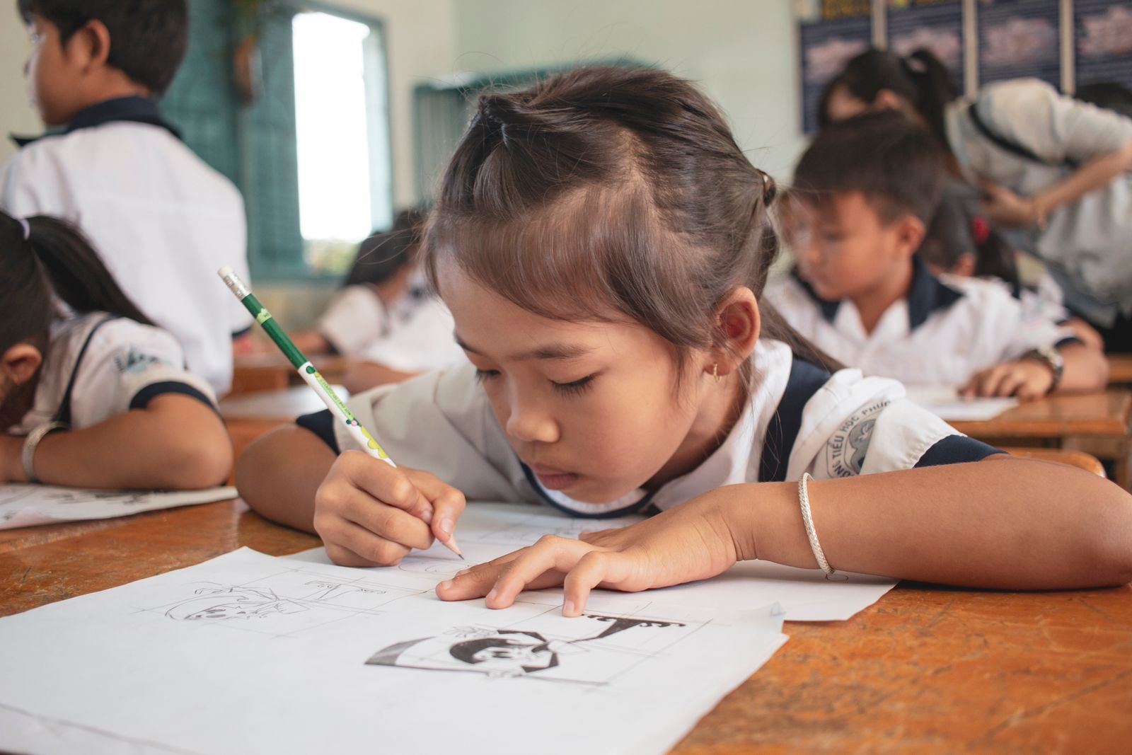 An elementary-aged student concentrating on a drawing in her classroom